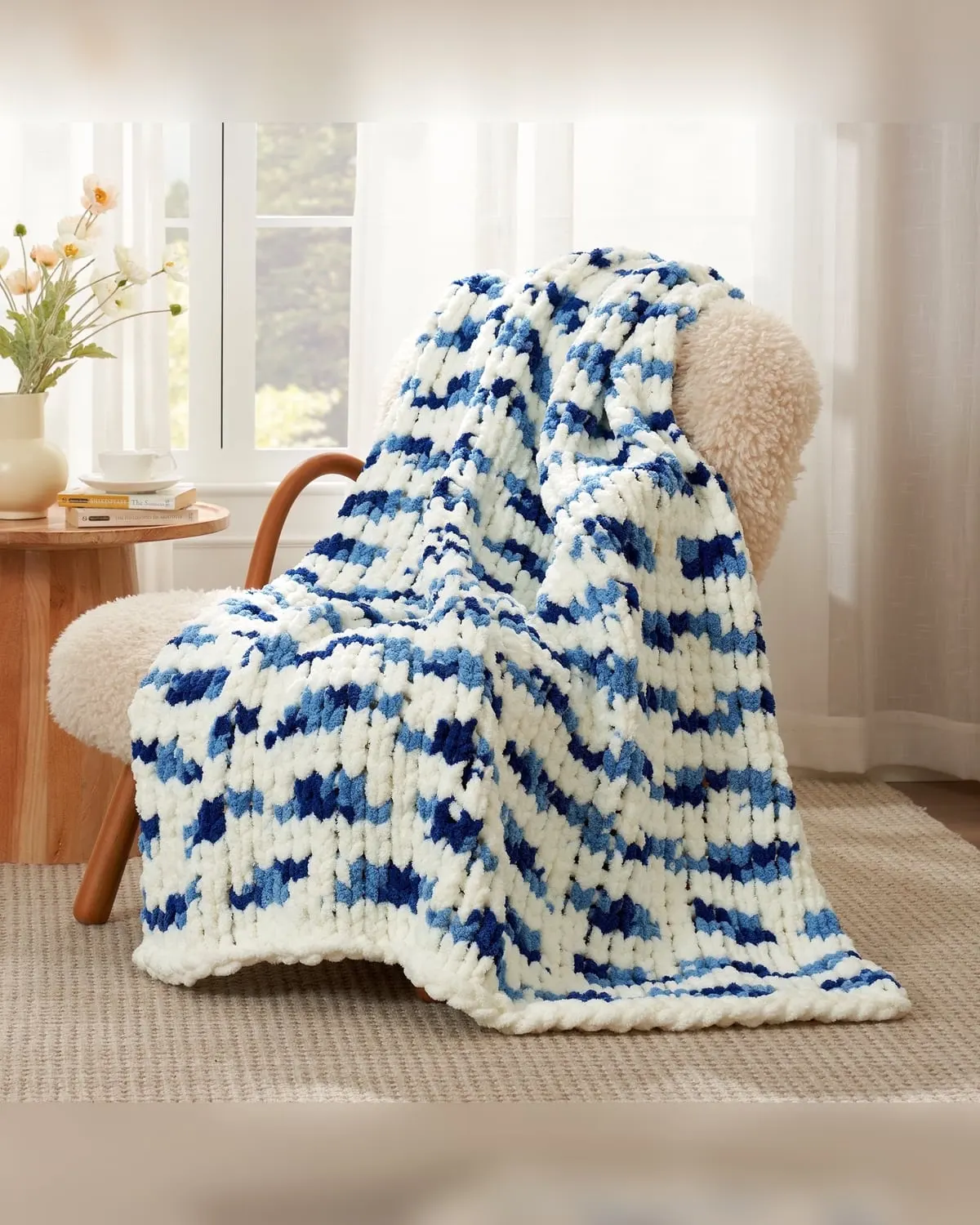 Chunky knit chenille throw blanket draped over an armchair beside a bright window