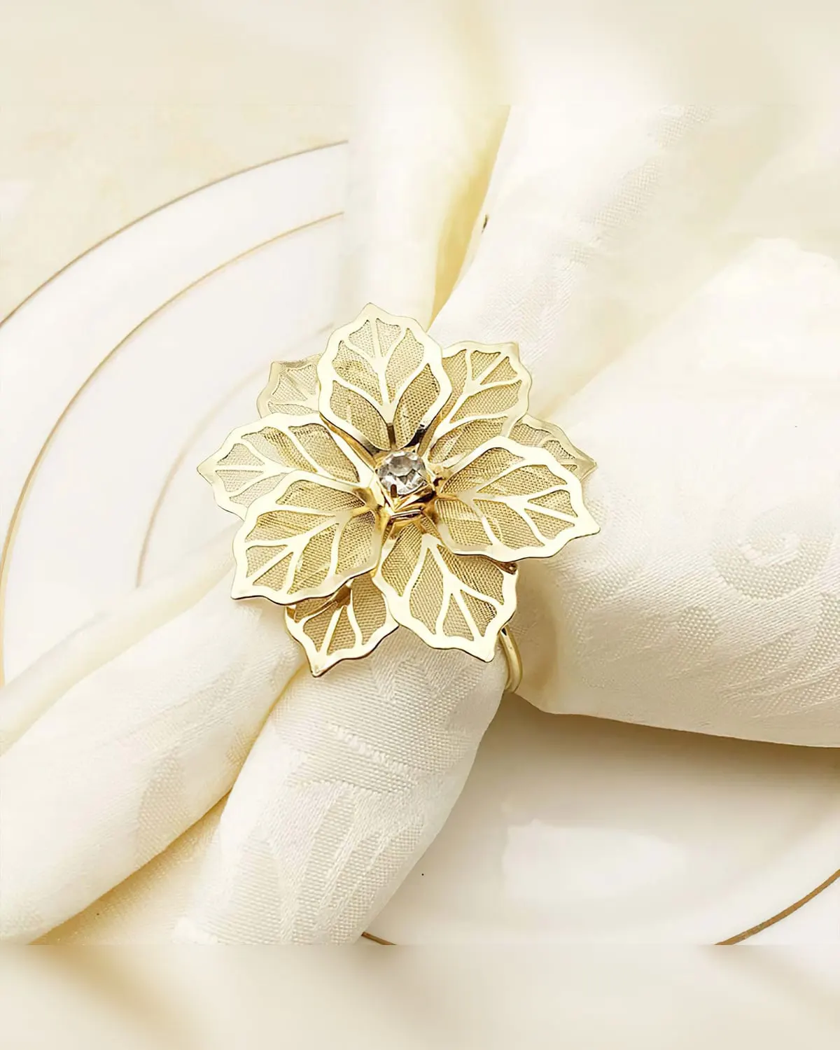 A gold flower napkin ring around a folded white napkin