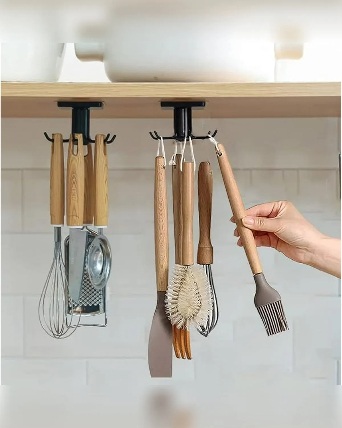 Rotating adhesive hooks holding kitchen utensils under a cabinet