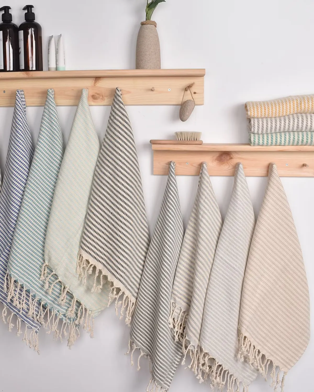 Striped Turkish cotton tea towels with knotted fringes hanging from a wooden peg rail