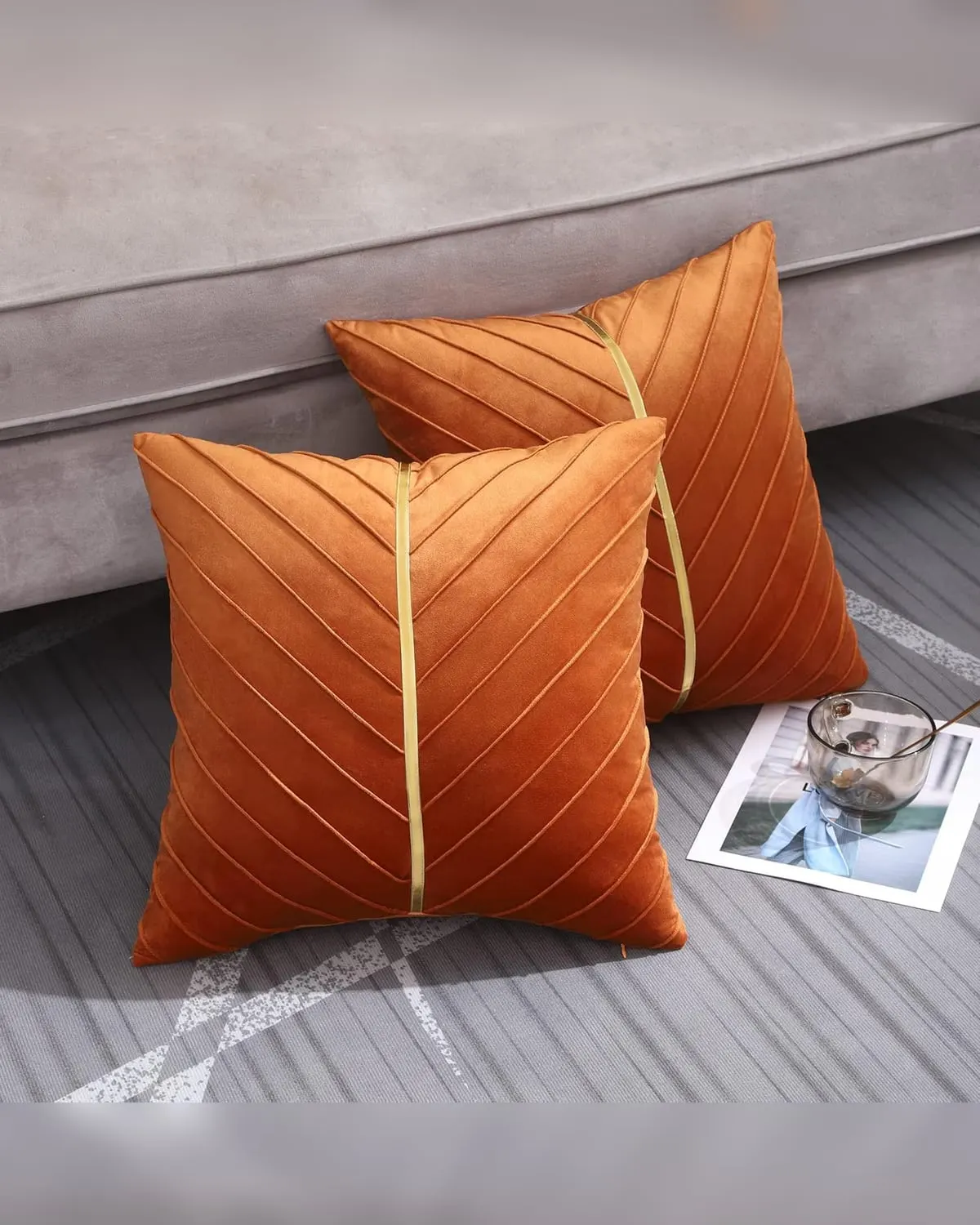 Two burnt-orange velvet throw pillow covers on a small sofa