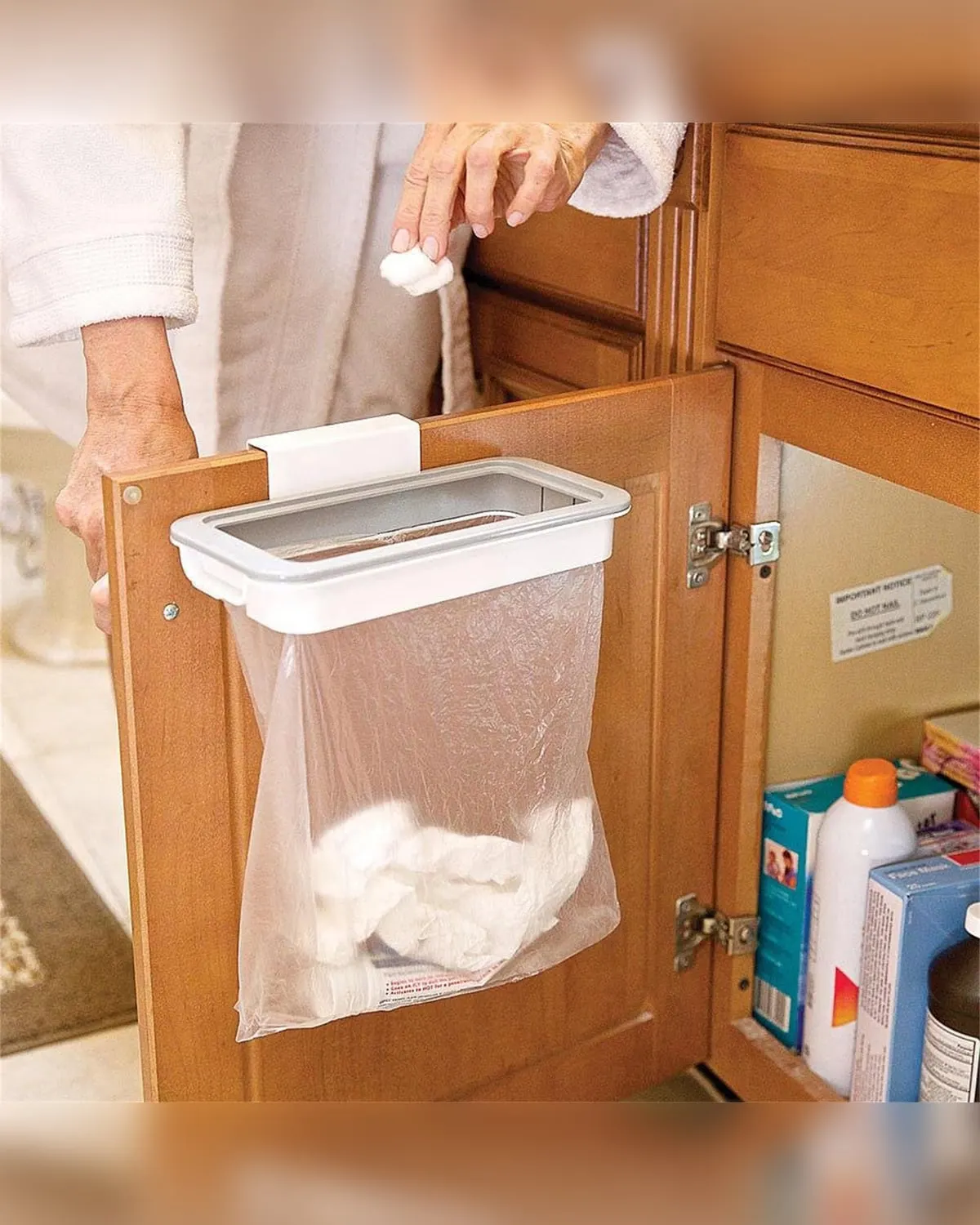 White over-cabinet-door rack holding a trash bag inside a cupboard