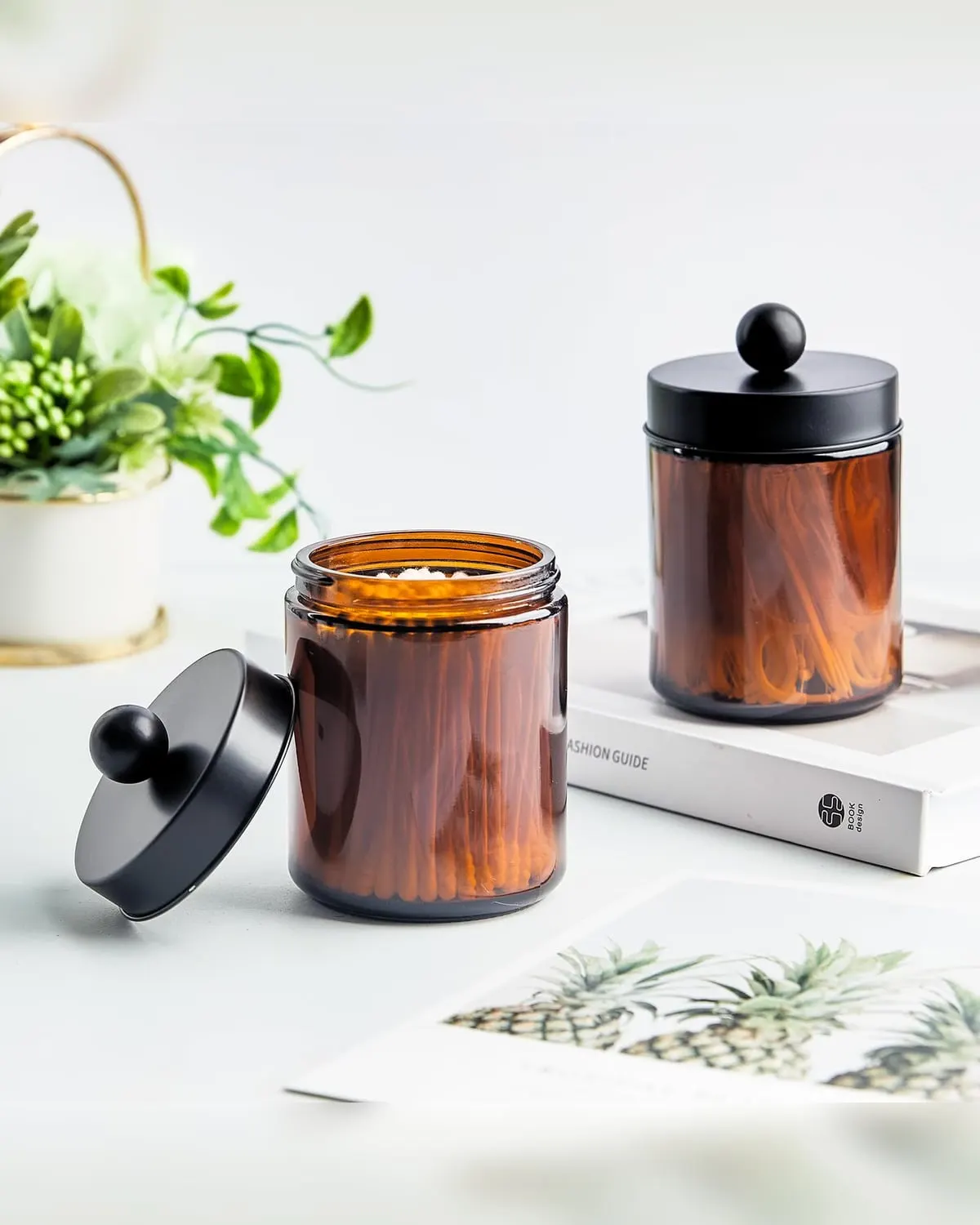 Two amber glass apothecary jars with lids on a small bathroom counter